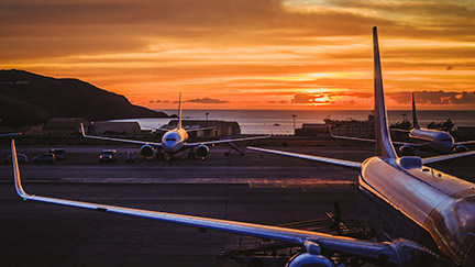 Aviones estacionados en un aeropuerto cercano al mar, contra un atardecer