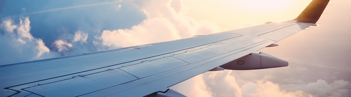 Ala de estribor de una avión contra un cielo parcialmente cubierto de nubes blancas