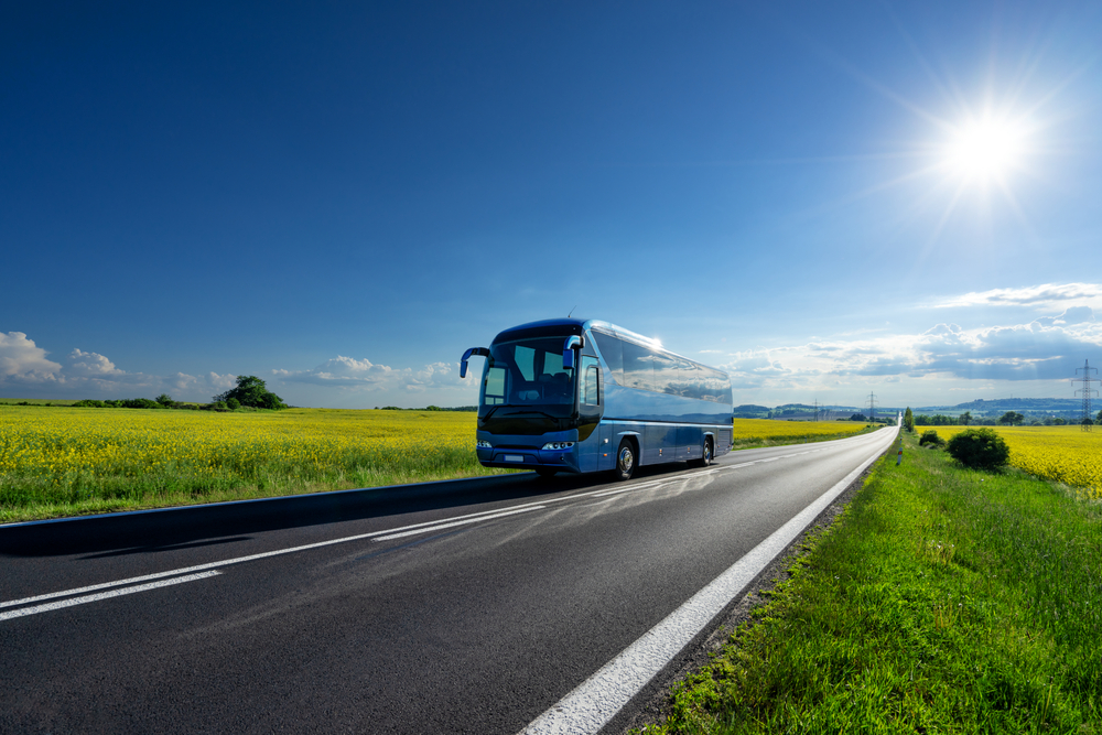 Autobús viajando por una carretera que atraviesa una zona de campo